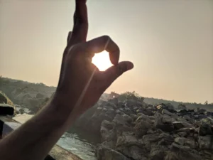 A hand reaching towards the sun, framed by the stunning landscape of Similipal National Park